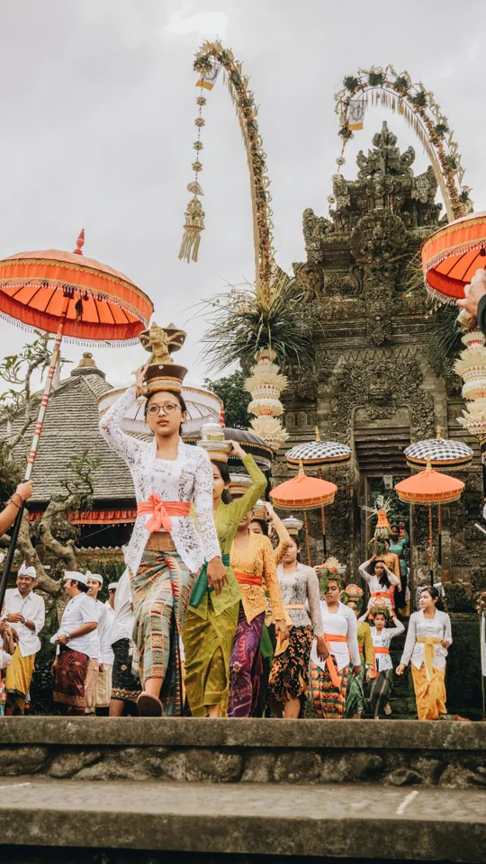 A ceremonial gathering with traditional dress and decorated bamboo poles