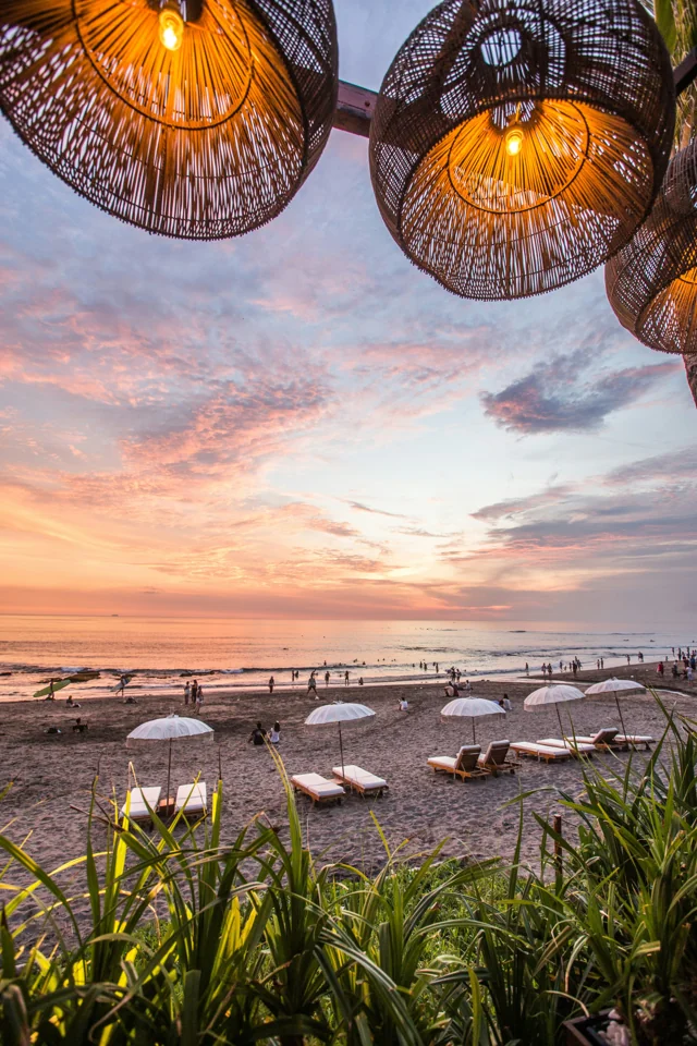 Sunset over a beach, with woven lamps in the foreground